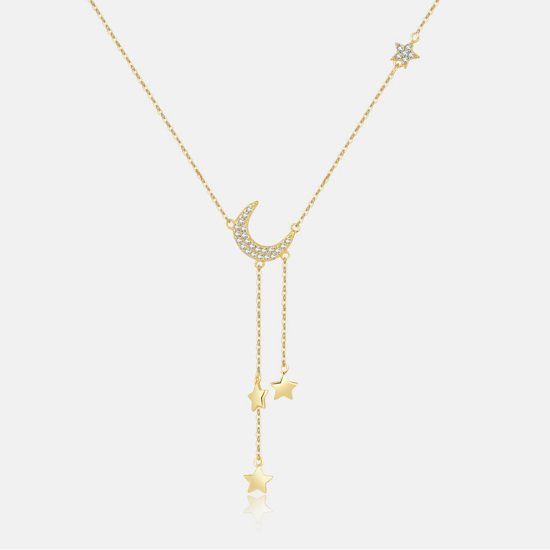 Gold necklace with star and moon pendants on a white background.
